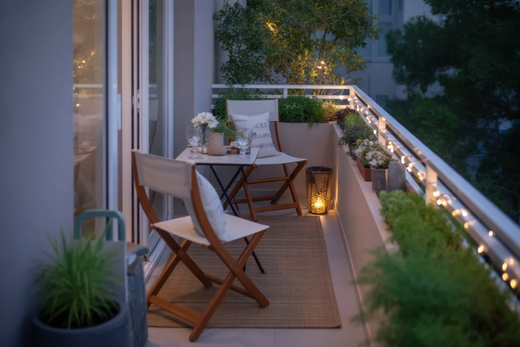 Cozy balcony setup with a small table, chairs, and string lights, creating a warm and inviting outdoor space.